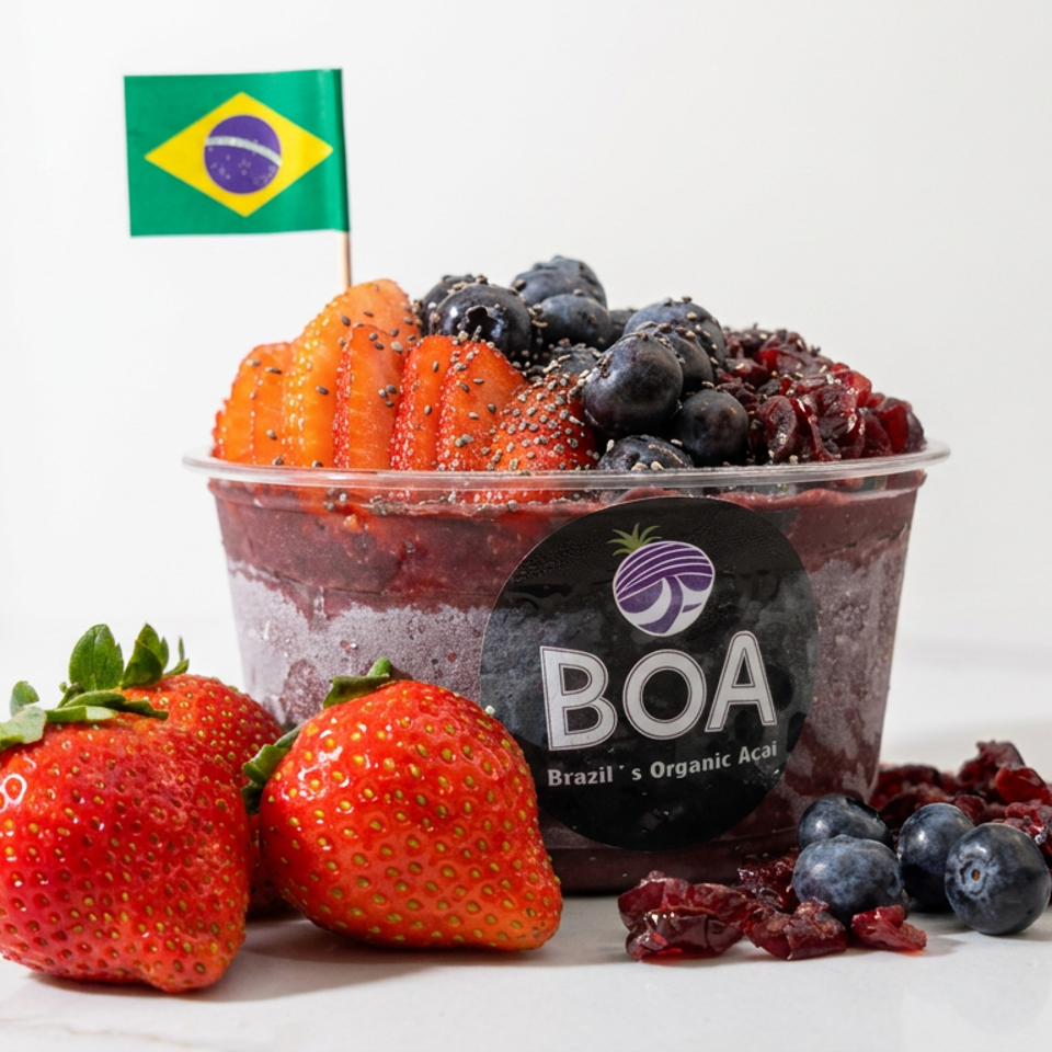 Brazilian açaí bowl topped with strawberries, blueberries, and dried cranberries, accompanied by fresh fruit and a Brazilian flag.